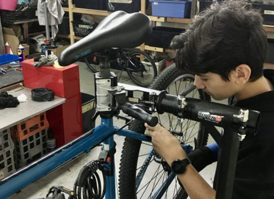 A young boy adjusts the rear brakes on a bike