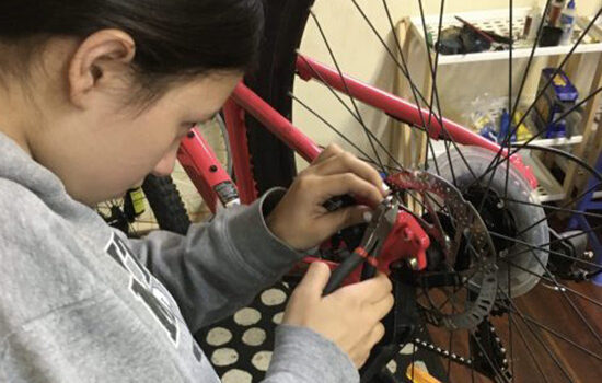 A girl adjusting the disc brakes on her bike