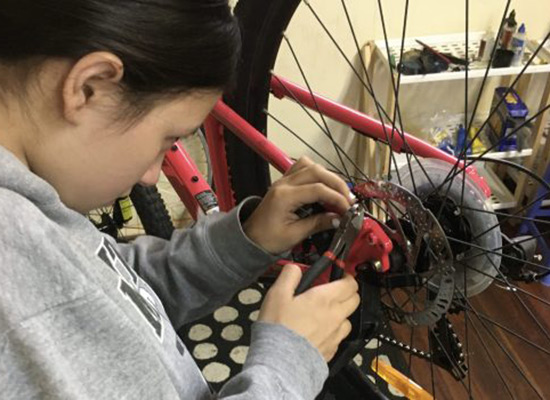 A girl adjusting the disc brakes on her bike